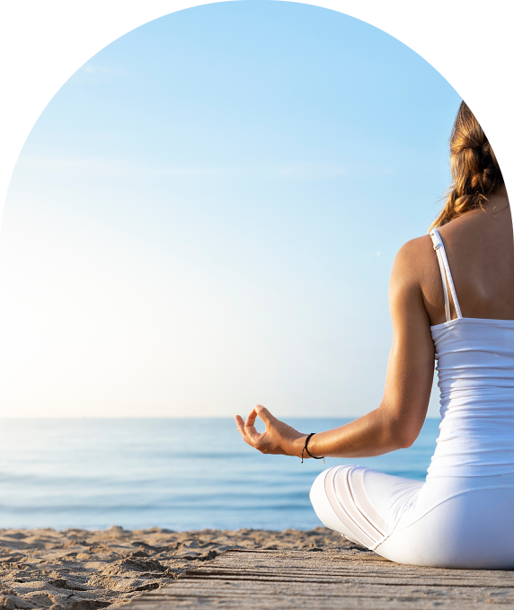 Person meditating on the beach during sunrise or sunset.